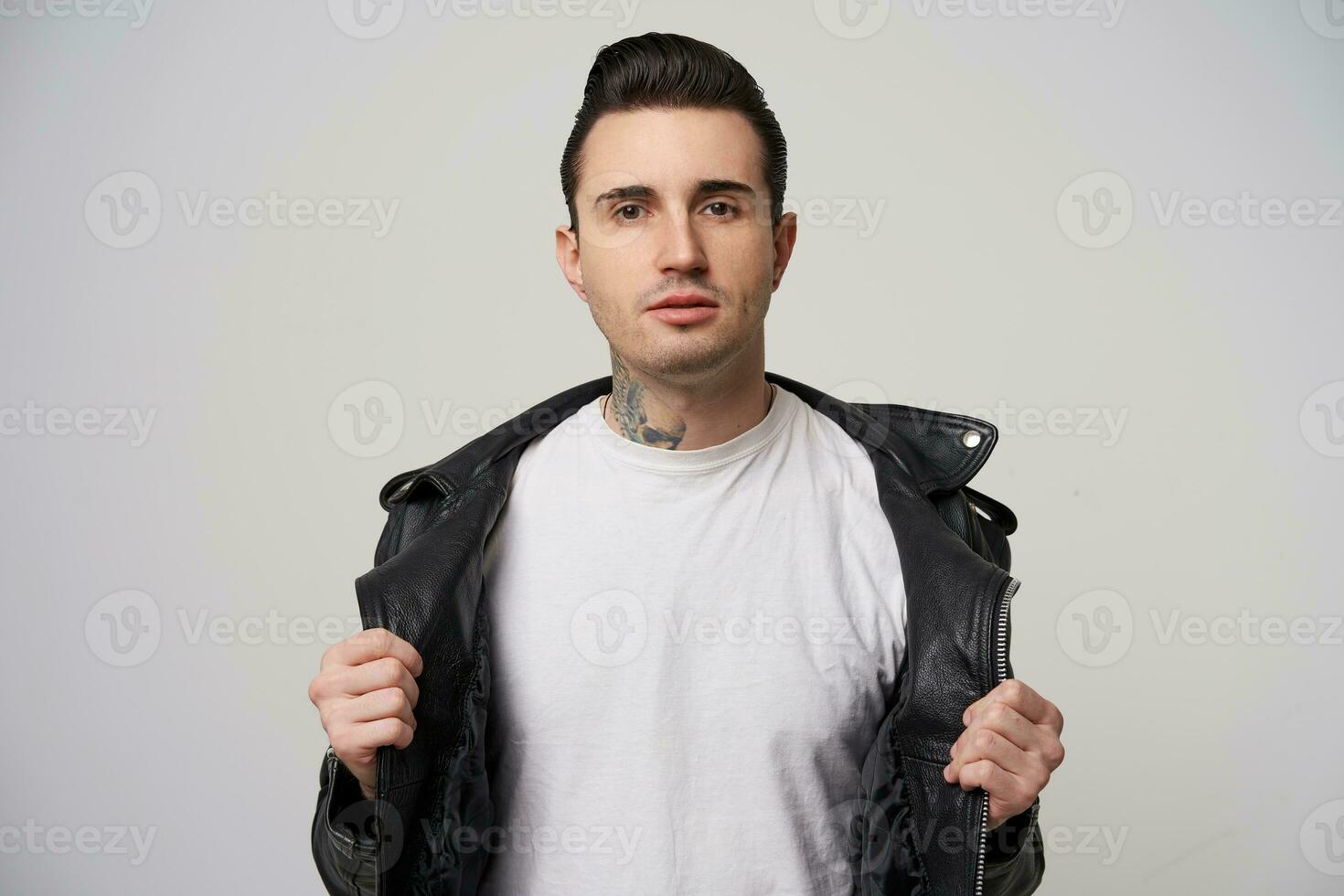 Young rebel, with a stylish haircut and styling with a briolin, tattoo on the neck, dressed in the style of 50s-60s,keeps hands like putting down black leather jacket and leaving blank white T-shirt photo