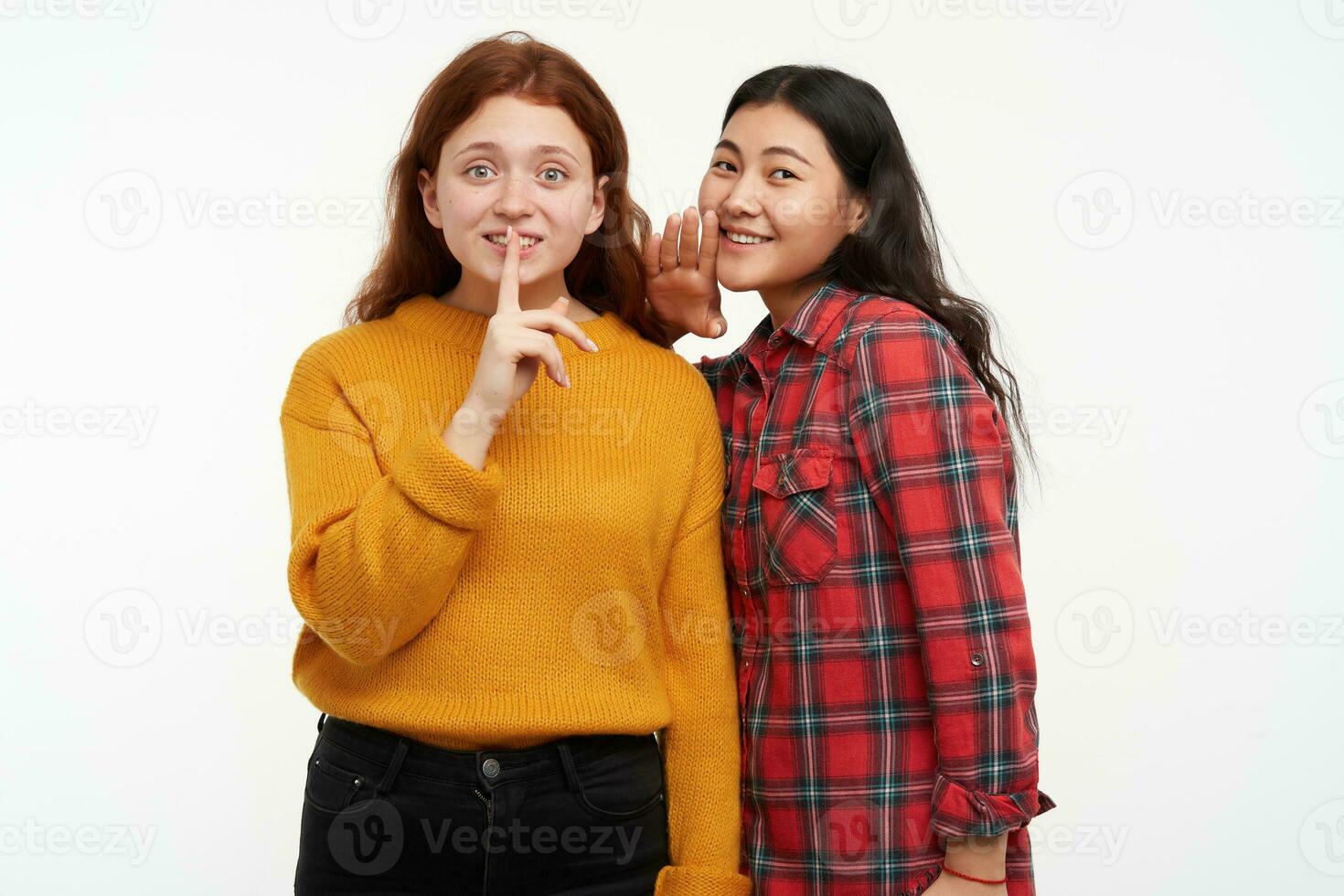 personas y estilo de vida concepto. dos hipster amigos. niña susurro a su amigo, demostración silencio signo. vistiendo amarillo suéter y a cuadros camisa. acecho a el cámara, aislado terminado blanco antecedentes foto