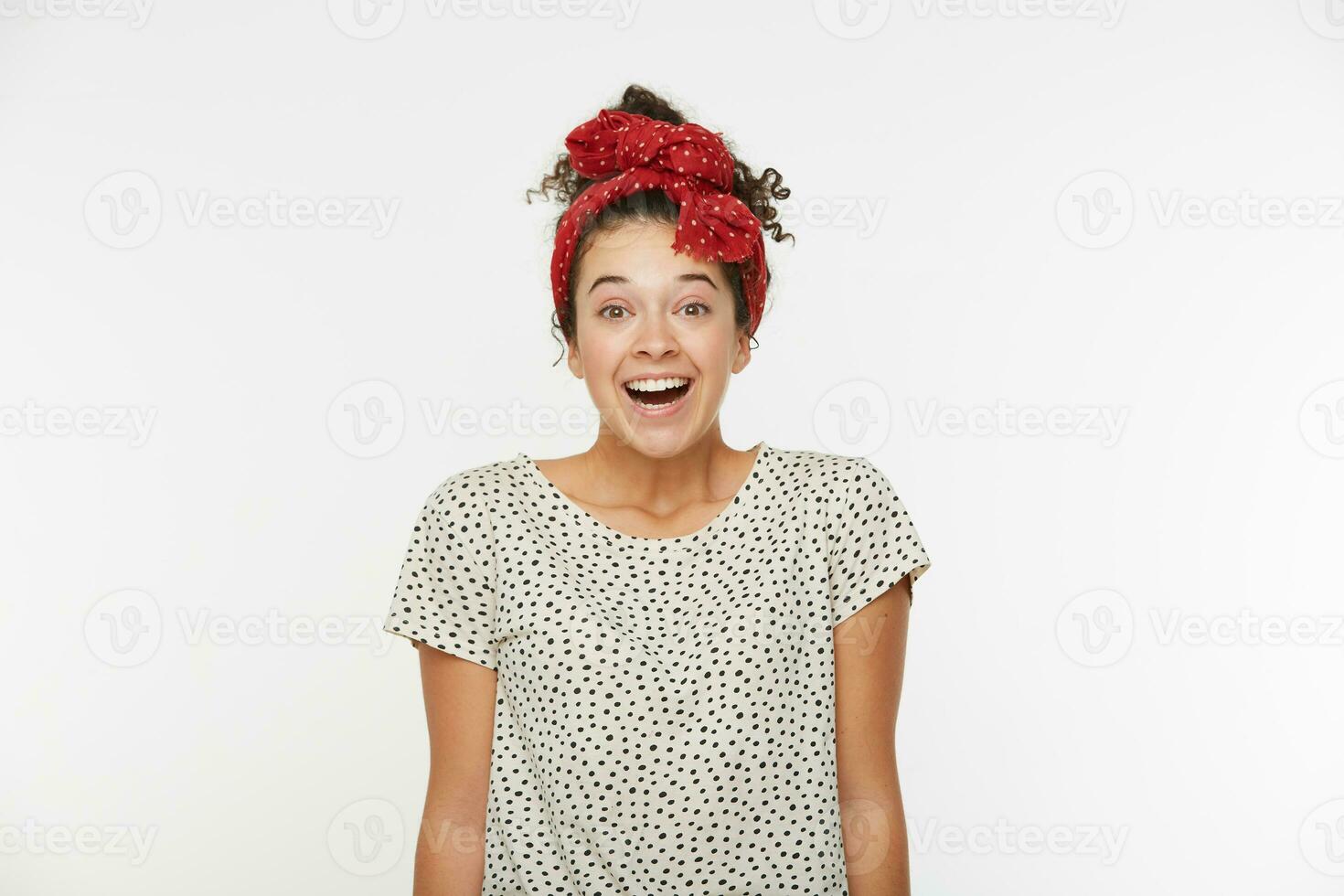 People, emotions and pleasant feelings concept. Beautiful young girl with joyful expression, smiles happily as watches funny programmer during spare time, wears T-shirt and red scarf with polka dots photo