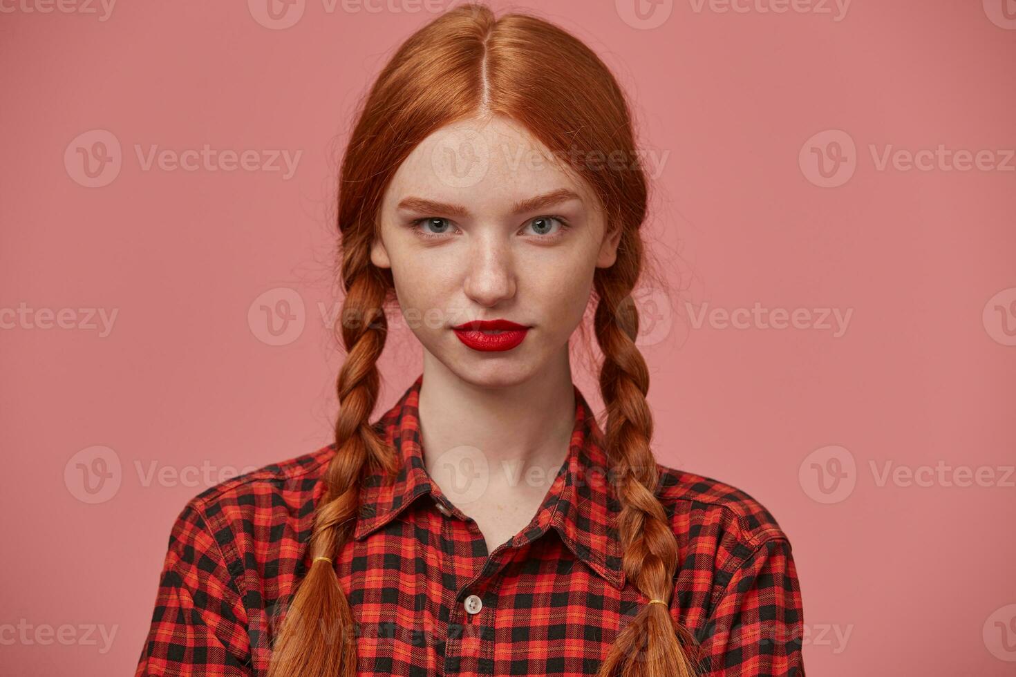 close up of young ginger female looks thoughtfully looks into camera, keeps calm and positive. photo