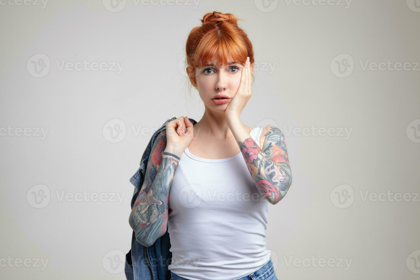 Indoor portrait of young ginger female posing over white wall photo