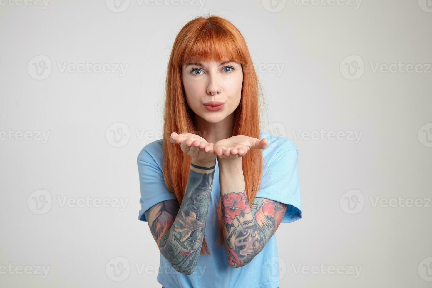 Indoor portrait of young ginger female posing over white wall send kiss into camera photo