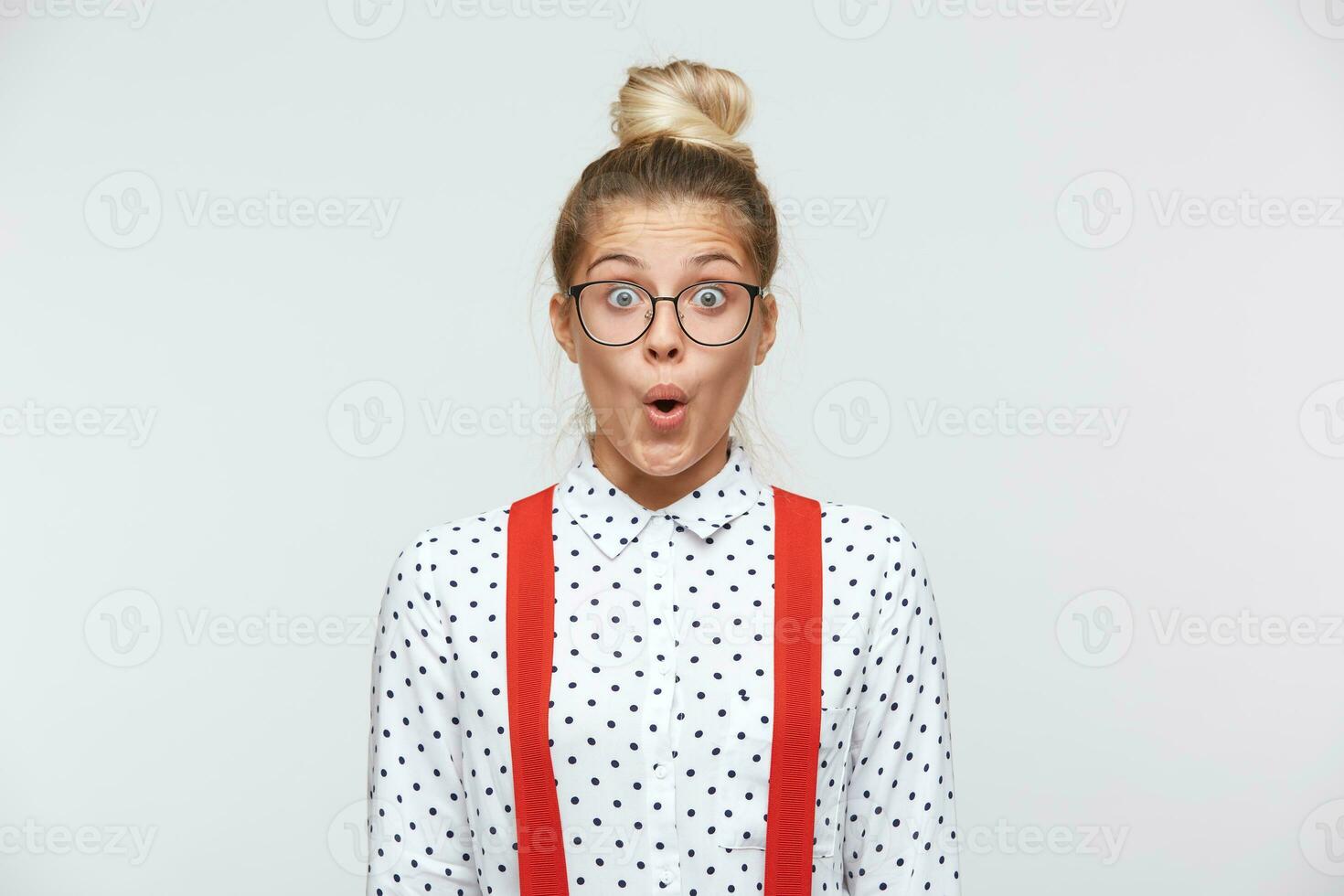 Surprised facial expression. Have look at that amazing thing Portrait of shocked female lowered jaw from surprise, feels stupefied, being impressed by something. In a white shirt, red suspenders photo