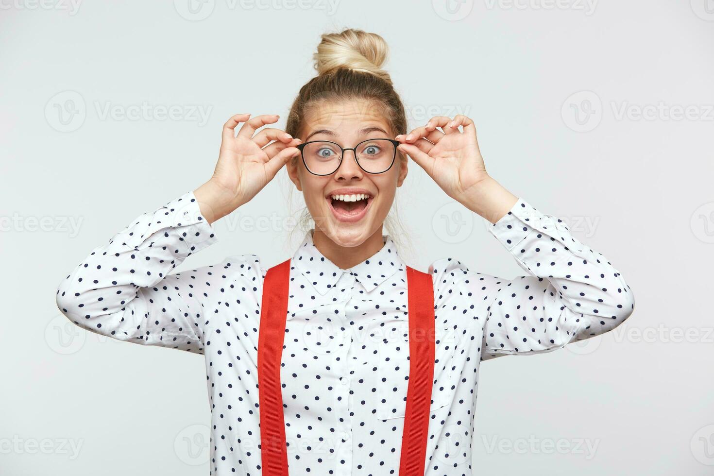 Portrait of a young woman holding glasses and looking at camera. Health and vision concept - joyful woman adjusting eyeglasses, feeling happy with diopters selection. Poor eyesight, vision concept. photo