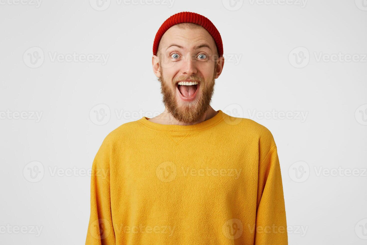 Close up of extremely happy overjoyed amazed bearded cool young man popping his eyes in surprisement, looking glad, dressed extraordinary informally,isolated over white background photo
