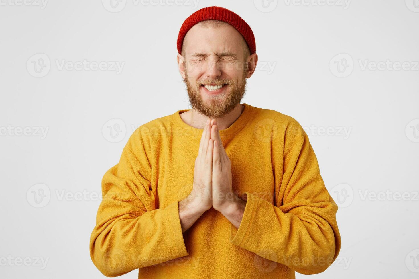 Picture of young guy dressed casually isolated on white background, having put hands together in prayer, looking concentrated with closed eyes, wishing dreaming and waiting for all best photo