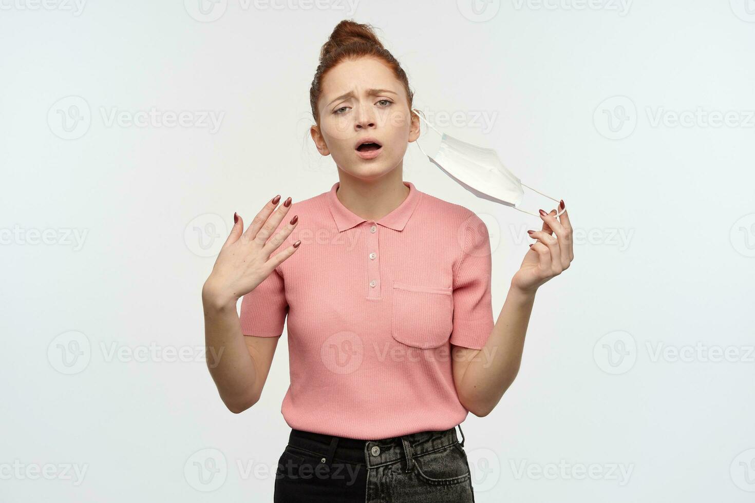 cansado, agotado pelirrojo niña con pelo bollo. vistiendo rosado camiseta. toma apagado médico cara mascarilla. respirar Fresco aire. siente alivio. acecho a el cámara, aislado terminado blanco antecedentes. foto