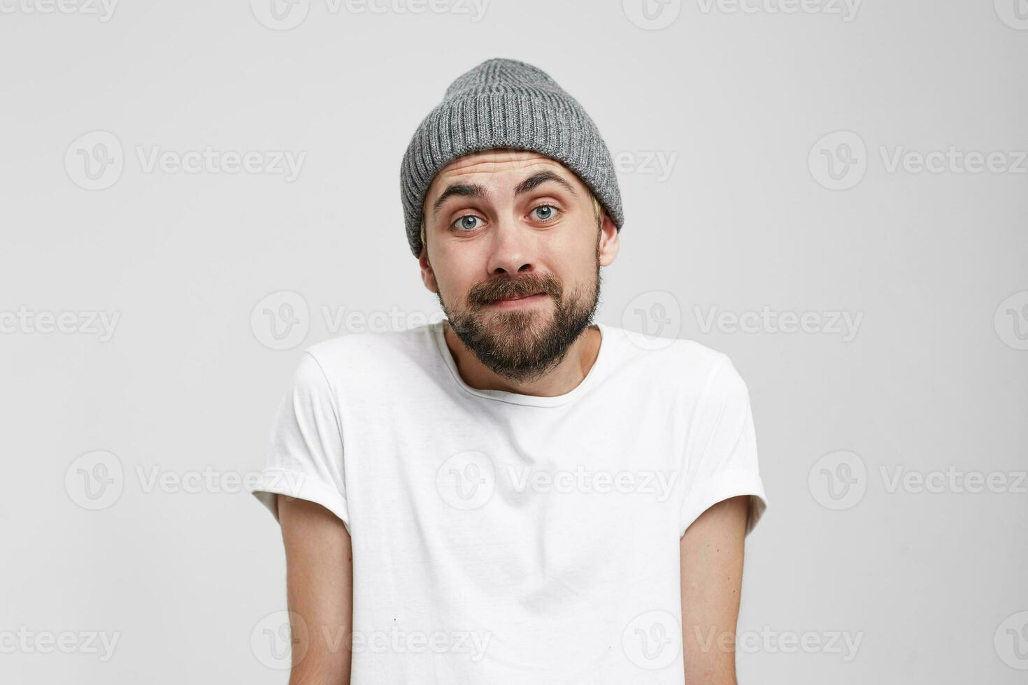 Guilty and confused young man shrugging shoulders, making helpless gesture with hands, having Oops expression on his face. Feeling sorry for doing something wrong,over white background photo