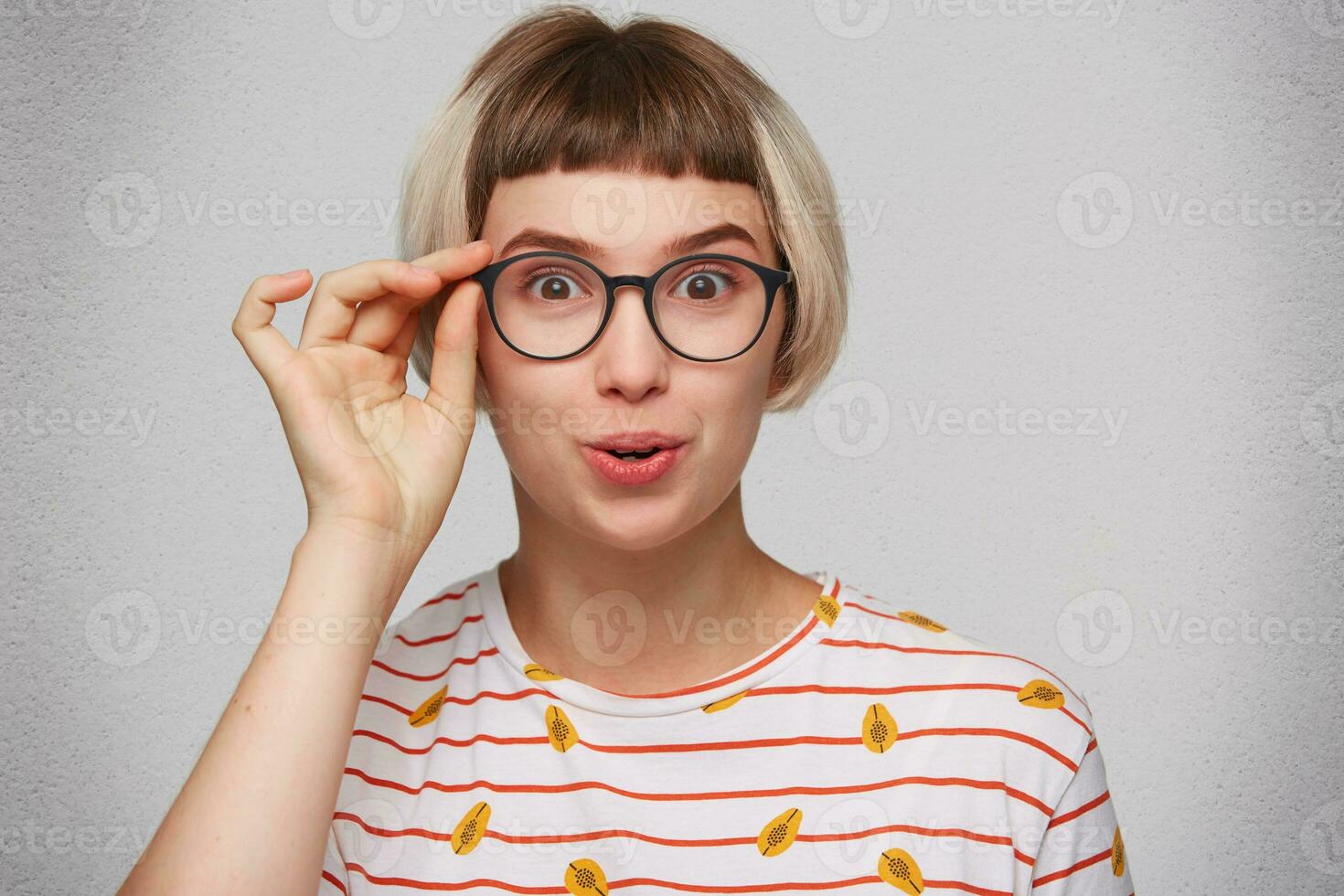 Closeup of happy surprised young woman wears striped t shirt and spectacles feels amazed and smiling isolated over white background photo