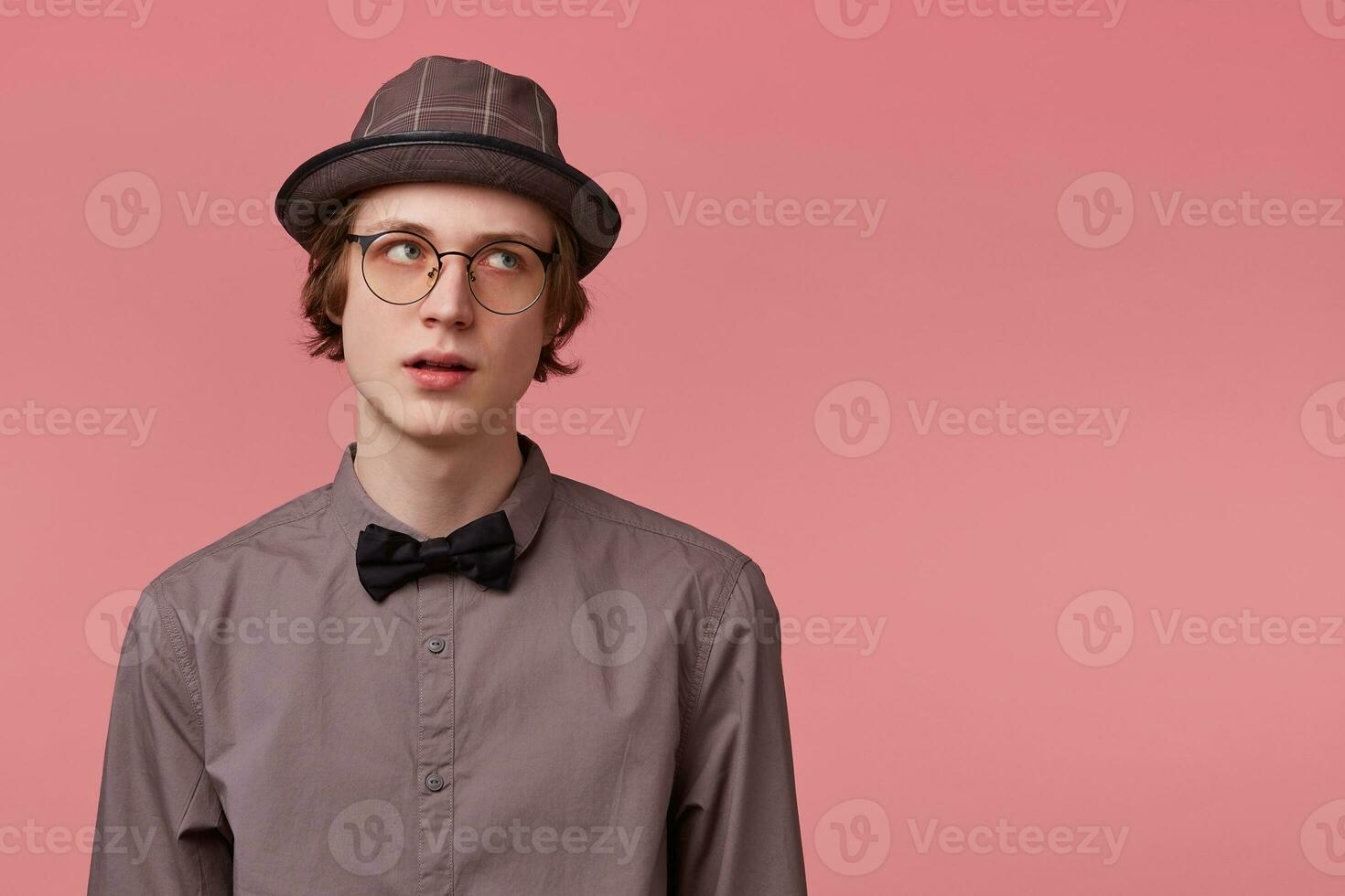 Dissatisfied young smartly dressed guy listen inattentively moralizing of his parents, turns away and looks rightside on blank copy space, over pink background photo