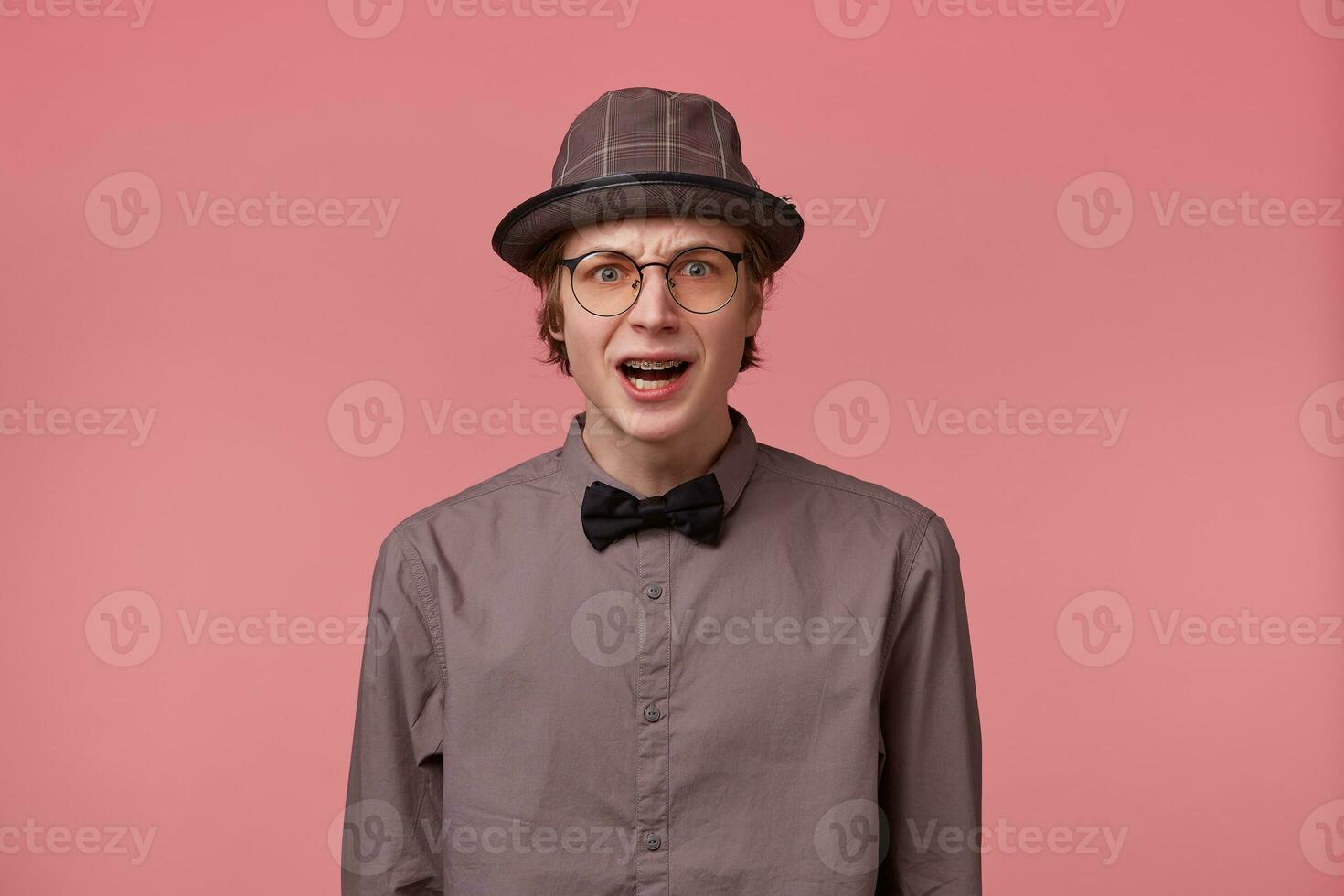 Stupefied guy looks with astonishment into camera, being amazed with incredible unbelievable positive news. Emotional hipster guy expresses surprisment, doesnt believe his eyes. Facial expression photo