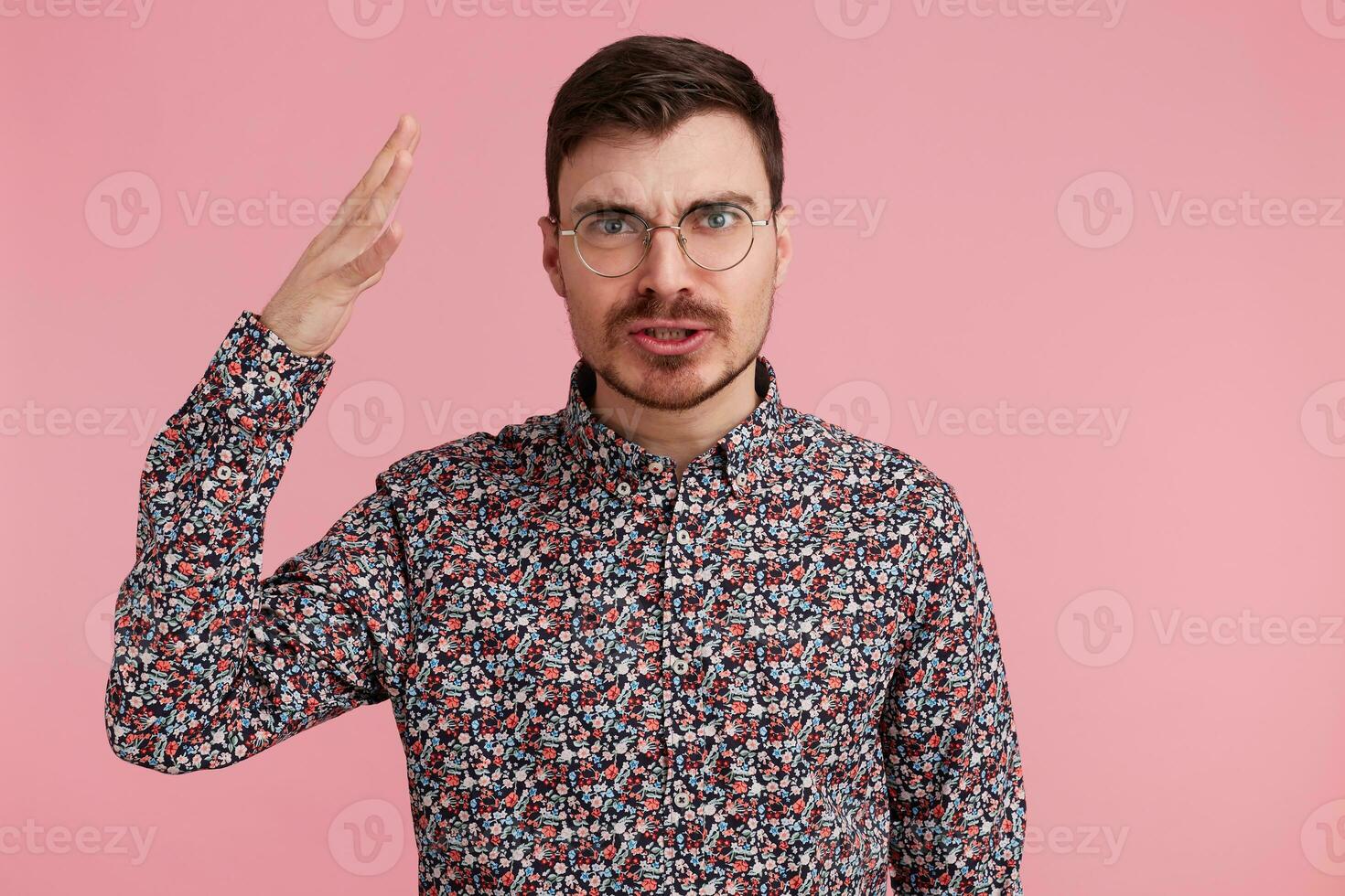 Portrait of young handsome bearded man with an angry, aggressive facial expression,has time how to prove his case, explains the point of view.Palm raised looking through photo