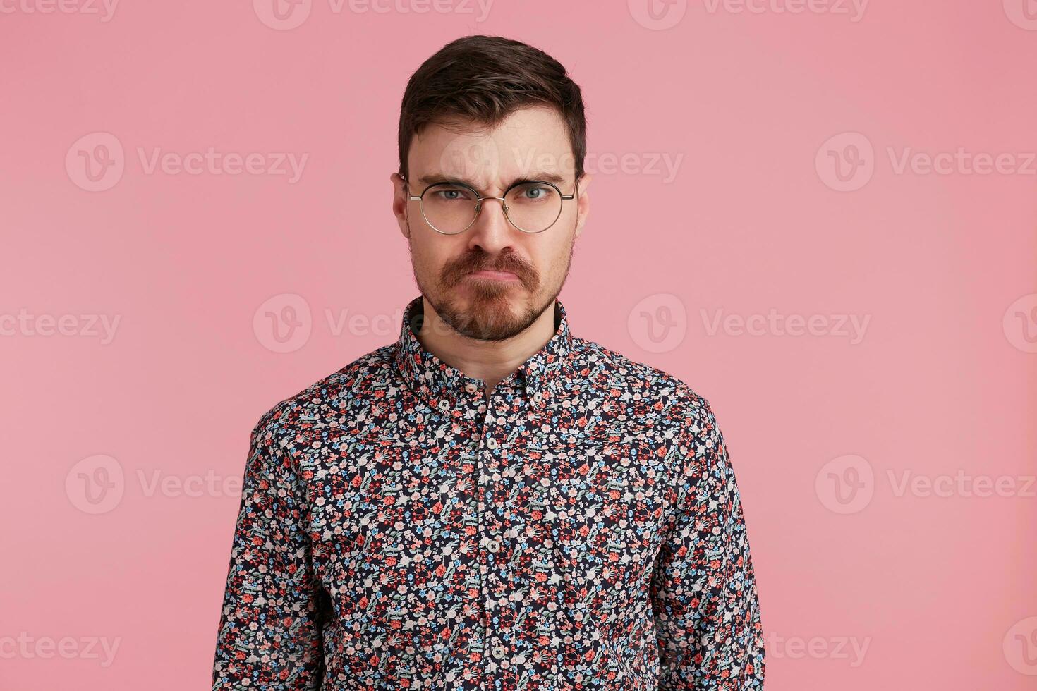 Young handsome bearded man with an angry, aggressive and facial expression, ready for the fight, showing furiousite and belligerent. photo
