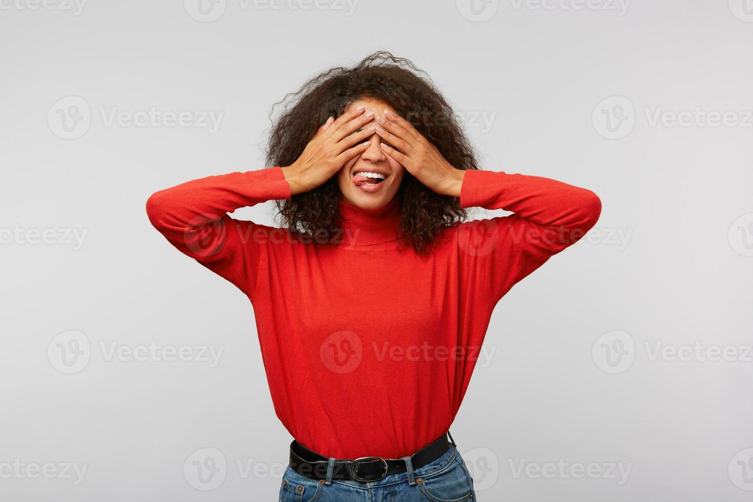Playful african american mother counting to ten while playing hide and seek with children. Portrait of charming happy woman with afro hairstyle covering eyes with palms and smiling broadly from joy photo