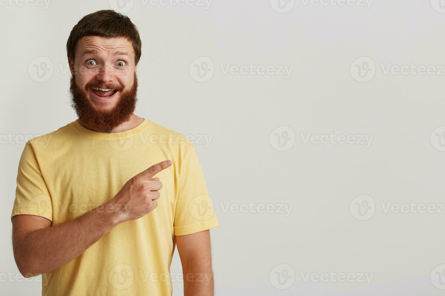Closeup of cheerful excited brutal young man with beard wears yellow t shirt photo