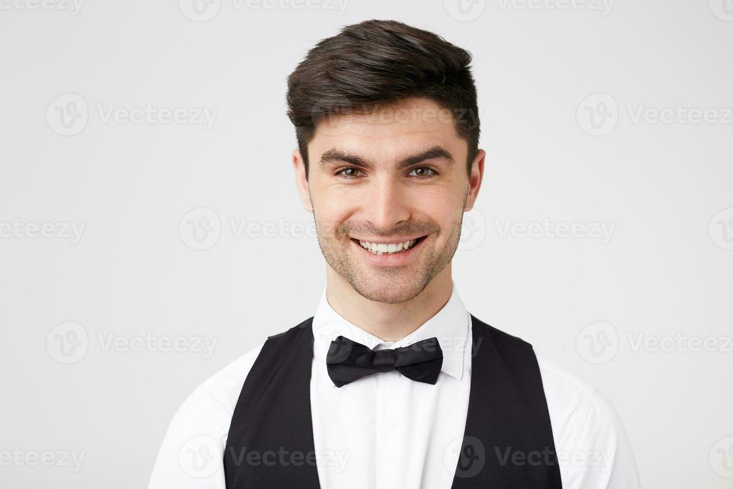 Nice attractive guy smartly dressed with black bowtie looking straight at the camera with a wide cheerful smile, looks happy contented, isolated on white background photo