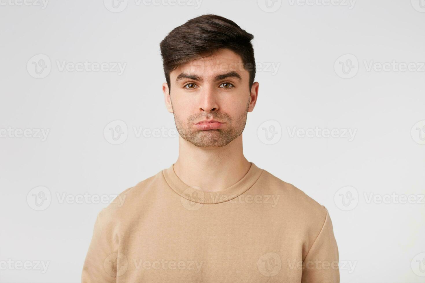 Cute attractive brunet with light stubble looks sad offended upset displeased. On the street bad weather and a date with his girlfriend canceled photo