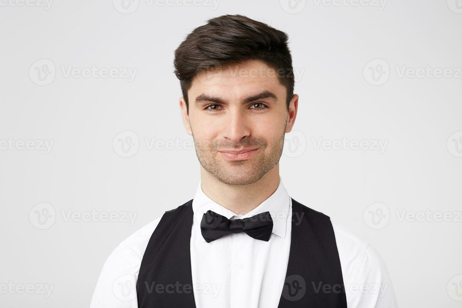 Confident flirting handsome smartly dressed dark-haired guy with black bow tie,looks charming inviting, all girls want to dance with him, isolated over white background photo