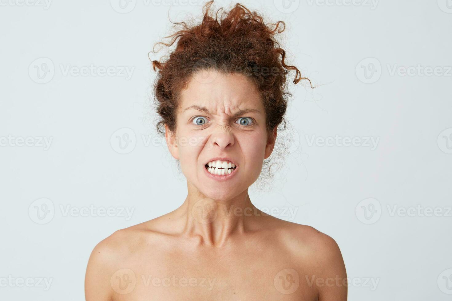 Cropped shot of mad furious young woman with curly hair and perfect skin looks angry an aggressive isolated over white background Feels angry and looks crazy photo