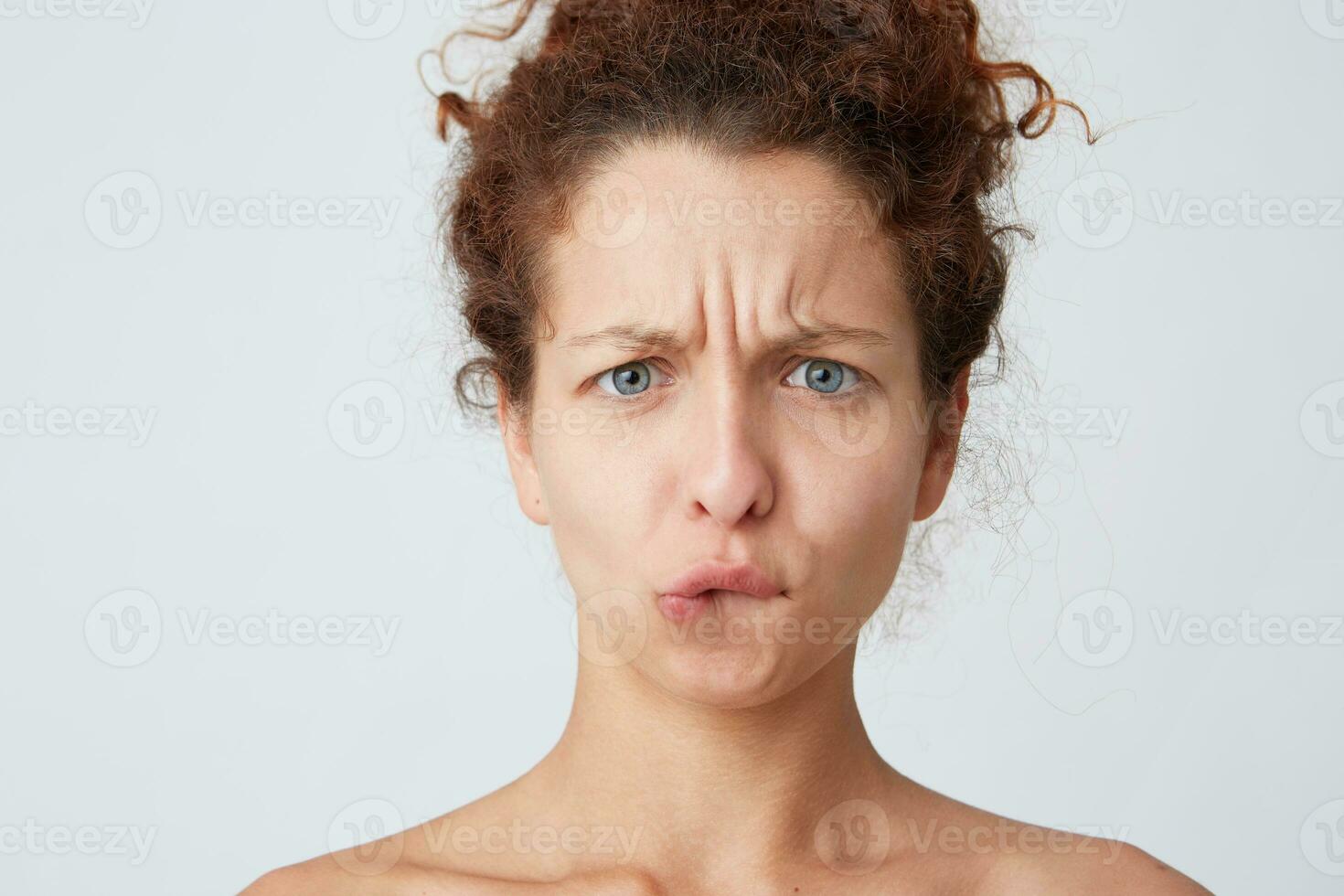 Cropped shot of worried thoughtful young woman with curly hair and healthy fresh skin looks stressed and biting her lip isolated over white background Standing half naked after shower photo