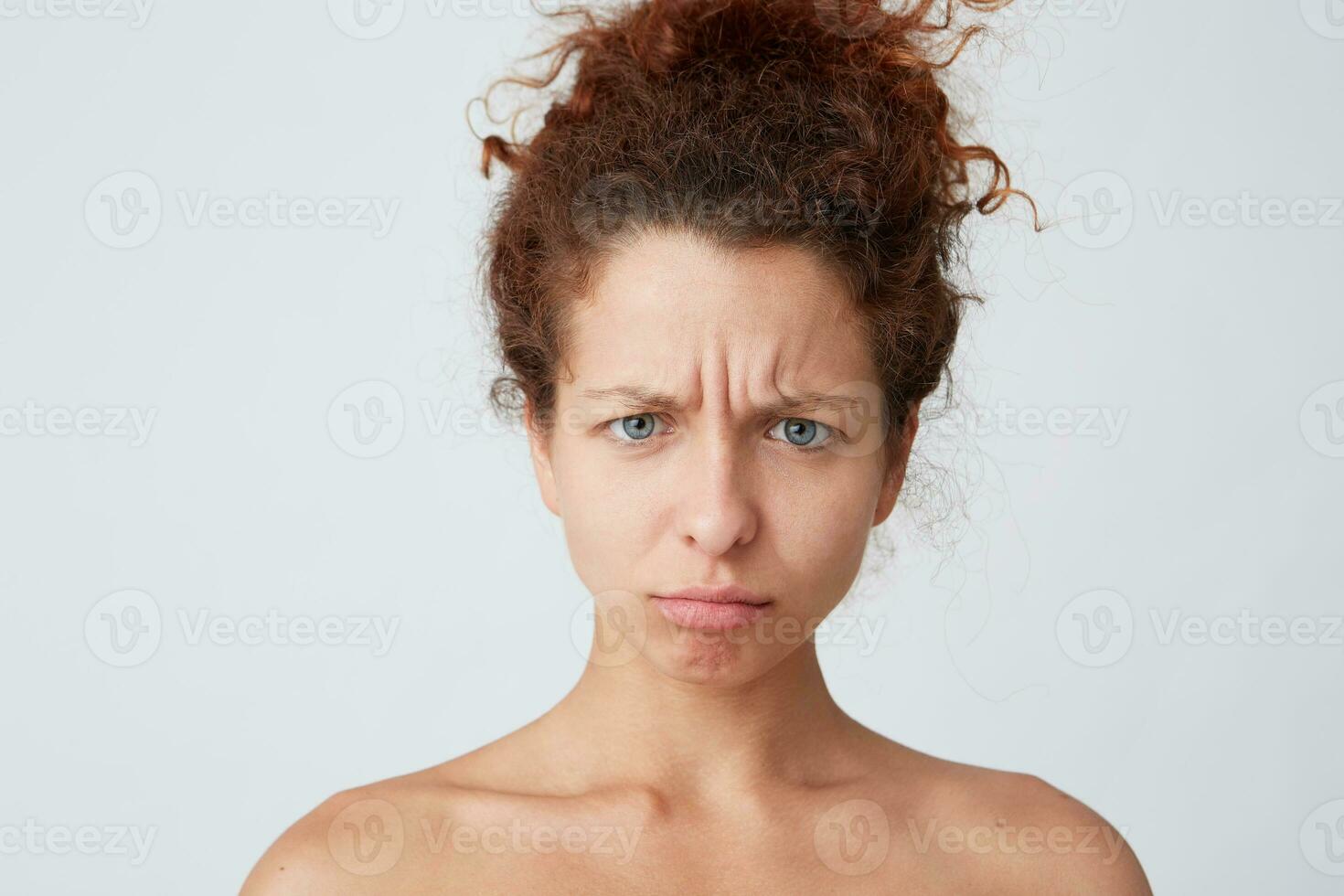 Horizontal shot of pensive confused young woman with curly hair and healthy skin standing half naked and looks worried isolated over white background Feels stressed and abused after shower photo