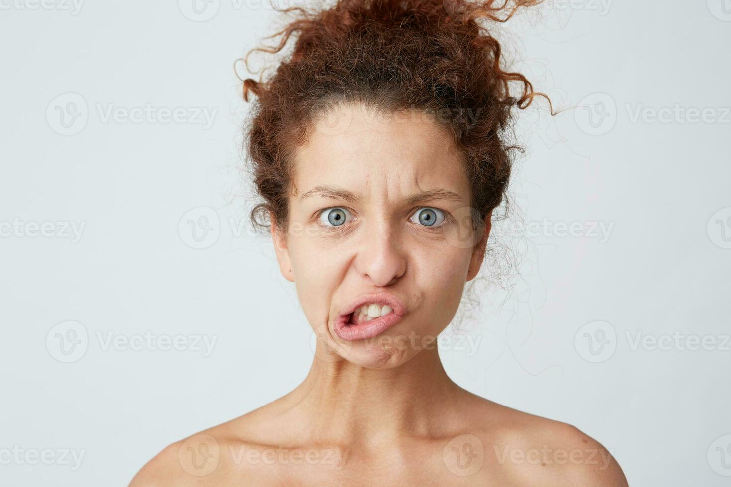 Close up shot of comical amusing young woman with curly hair and healthy skin making unhappy funny face and having fun after taking shower isolated over white background photo