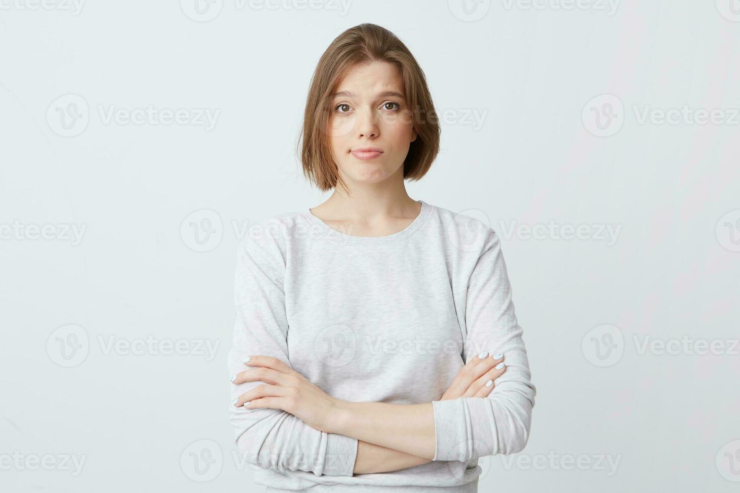 Unhappy dissatisfied young woman in long-sleeve standing with hands folded and feels disappointed isolated over white background photo