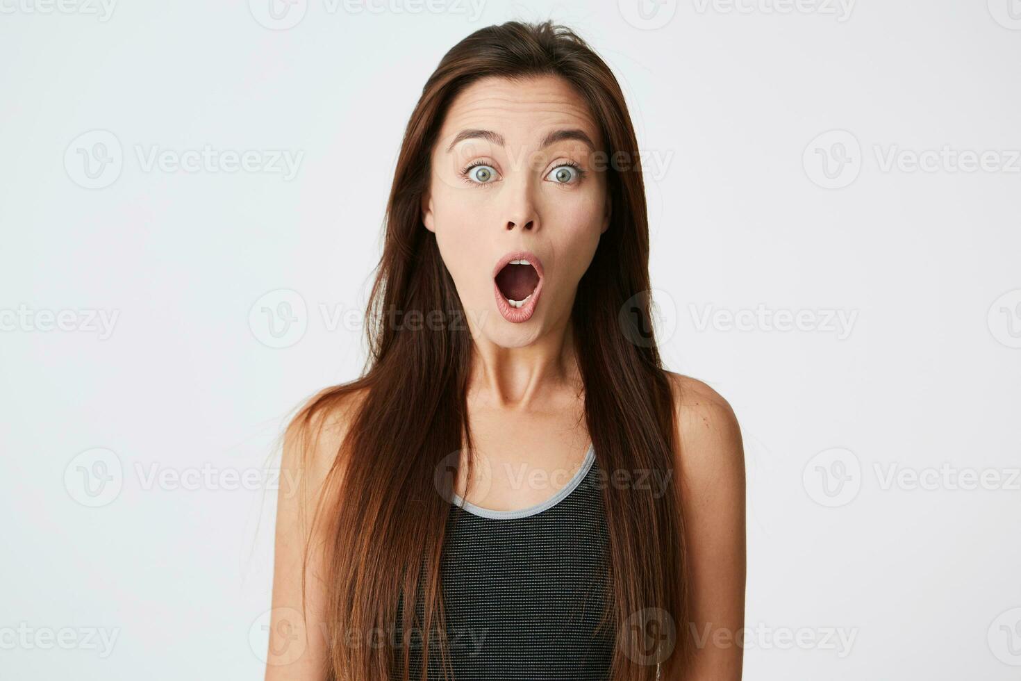 Portrait of shocked stunned young woman with long hair and opened mouth looking amazed and shouting isolated over white background photo