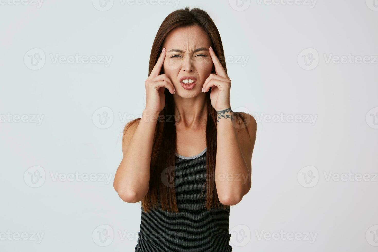 Portrait of upset desperate young woman with long hair touching her temples and suffering from headache isolated over white background photo