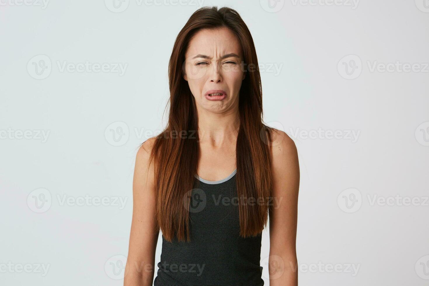 Upset hysterical young woman with long hair feels depressed and crying isolated over white background Looks offended and desperate photo