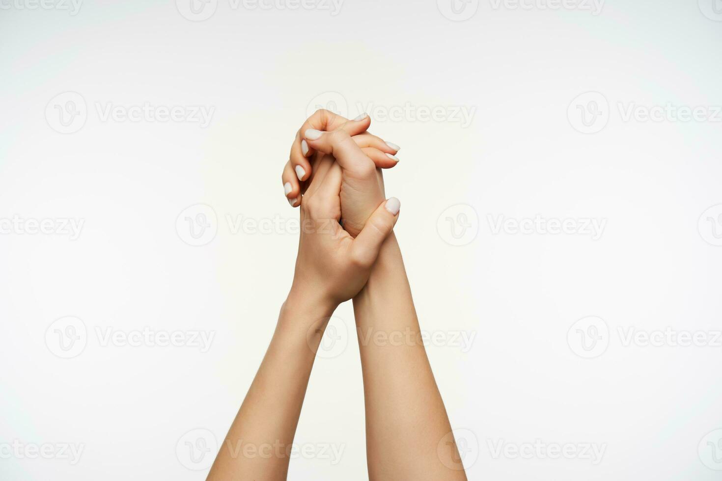 Horizontal shot of elegant woman's arms being raised against white background and folded together. Women showing hand with sign language photo