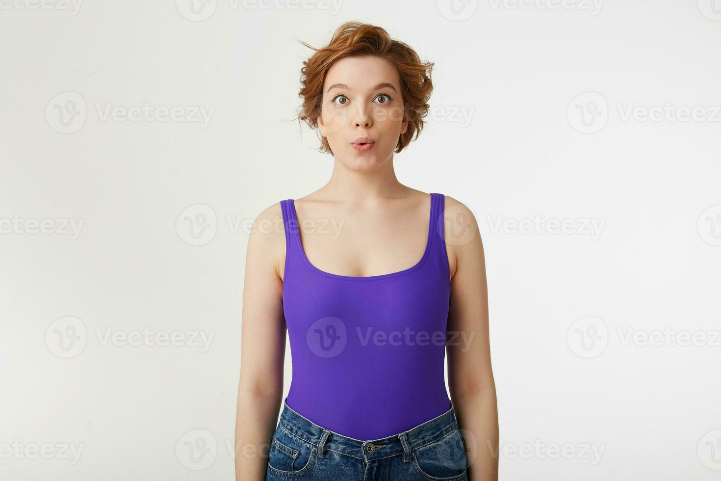 Portrait of a young happy amazed attractive short-haired girl, wearing a purple jersey, looking at the camera and speaks lips wow isolated over white wall. photo