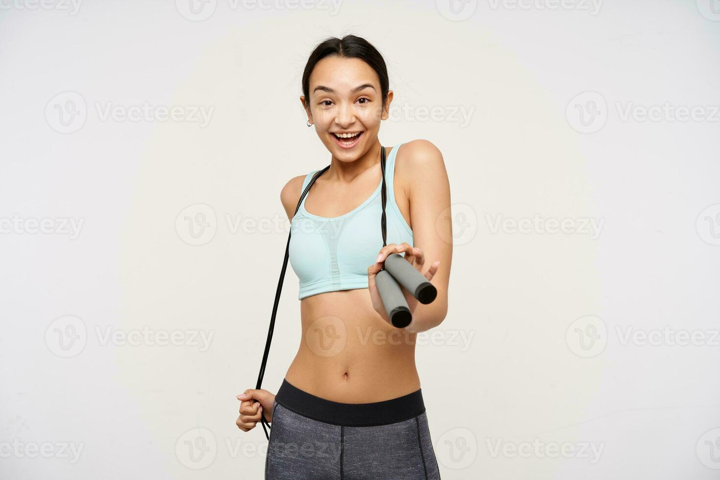 joven dama, bonito asiático mujer con oscuro largo cabello. vistiendo ropa de deporte y participación un saltar cuerda terminado su cuello. alegre, yendo a ejercicio. acecho a el cámara aislado terminado blanco antecedentes foto