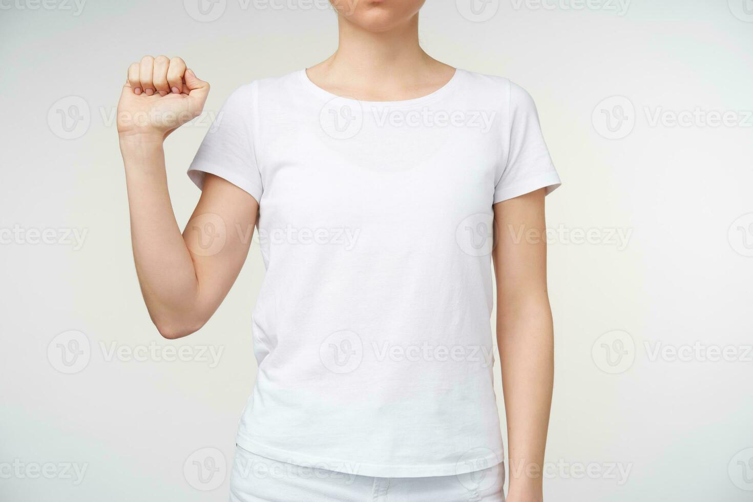 Indoor photo of young lady in casual clothes keeping hand raised while learning sign language, isolated over white background. Hand gestures of people with hearing impairment