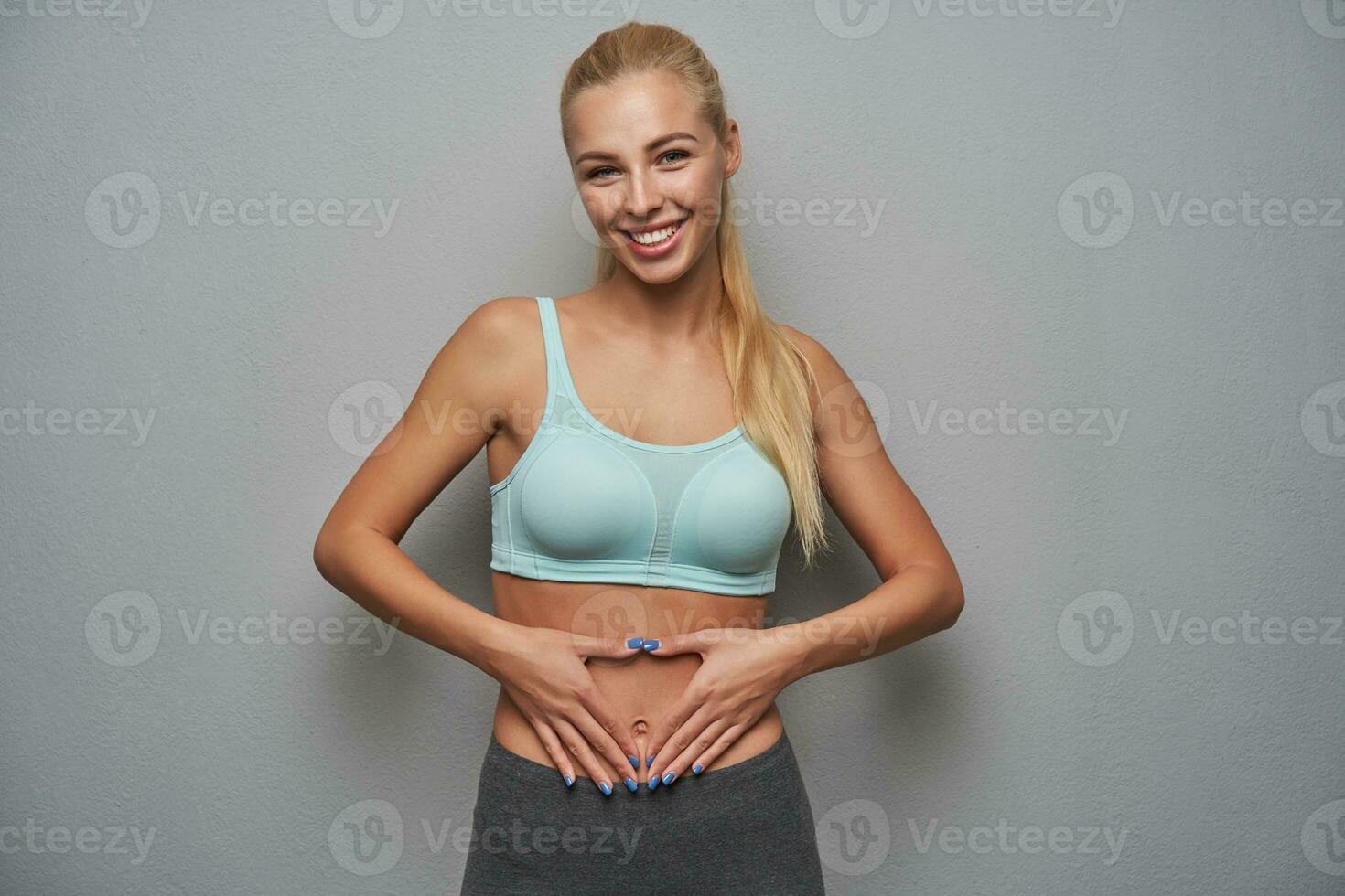 Studio photo of attractive sporty young lady with long blonde hair wearing mint top
