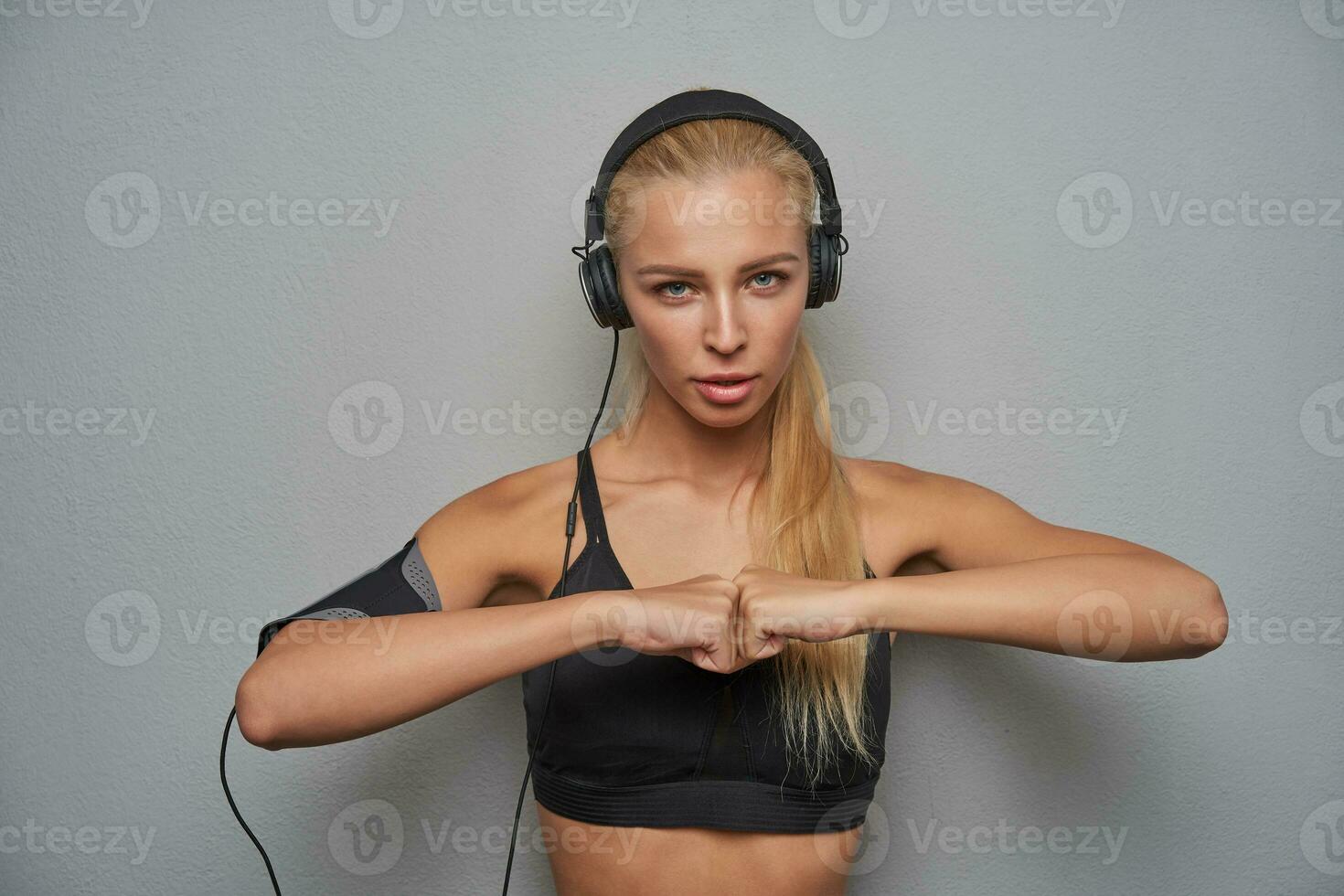 Portrait of serious young blonde long haired lady dressed in black sporty top looking at camera photo