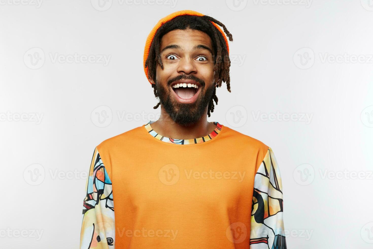 Agitated young lovely brunette man with dark skin looking excitedly at camera with wide eyes and mouth opened, standing over white background in casual wear photo