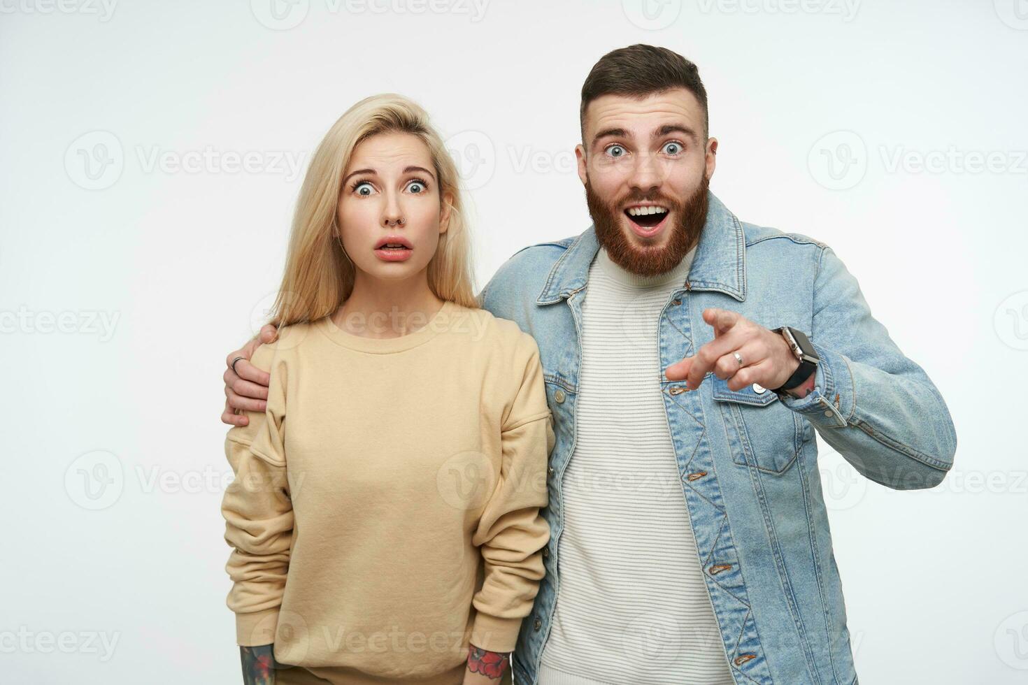 interior foto de joven de ojos azules bonito Pareja mirando a cámara con conmocionado caras mientras en pie terminado blanco fondo, vistiendo beige camisa de entrenamiento y pantalones Saco