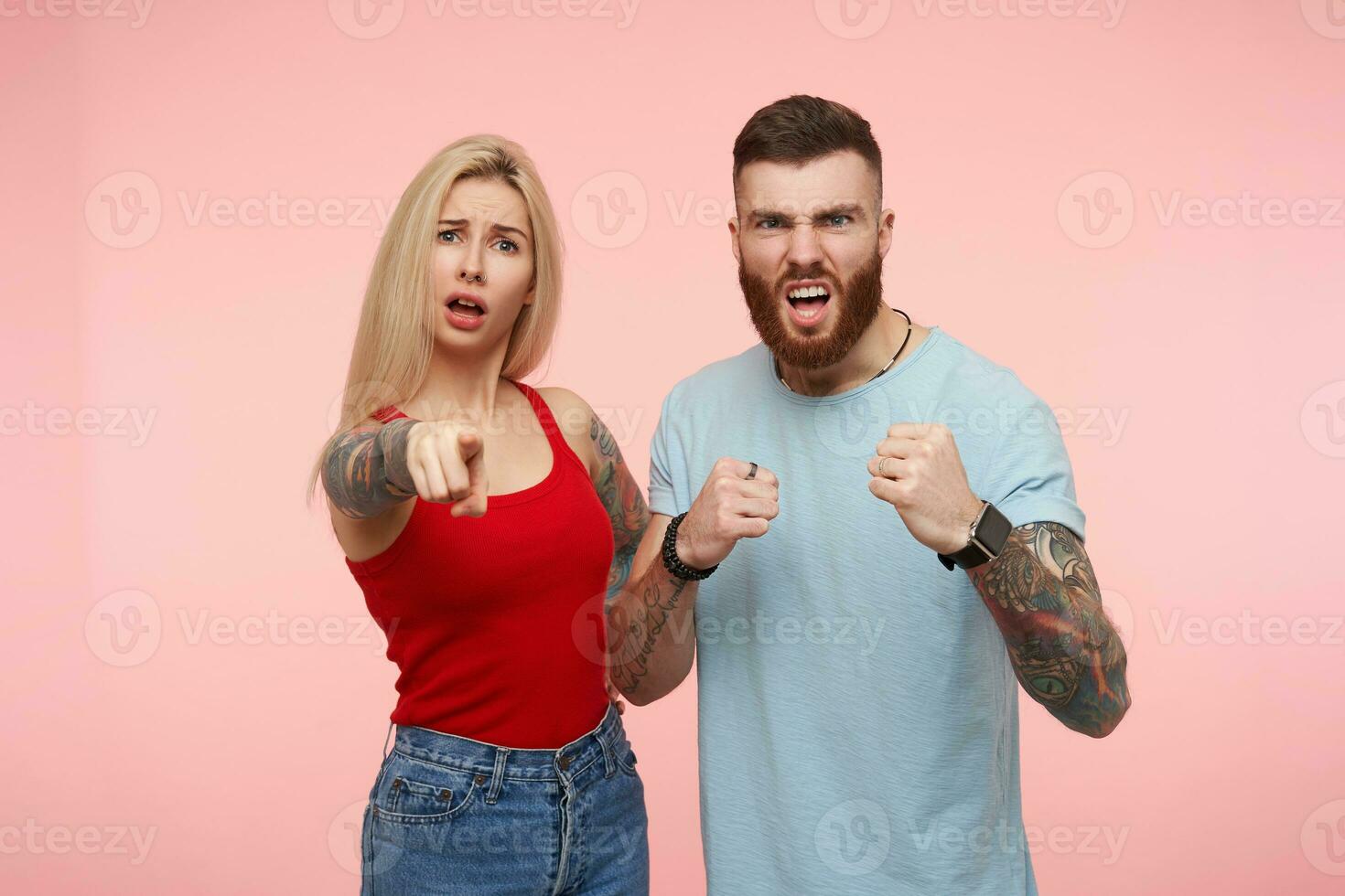 ofendido joven bonito largo peludo rubia hembra demostración a su grave enojado morena barbado chico alguien quien hecho su triste, aislado terminado rosado antecedentes foto