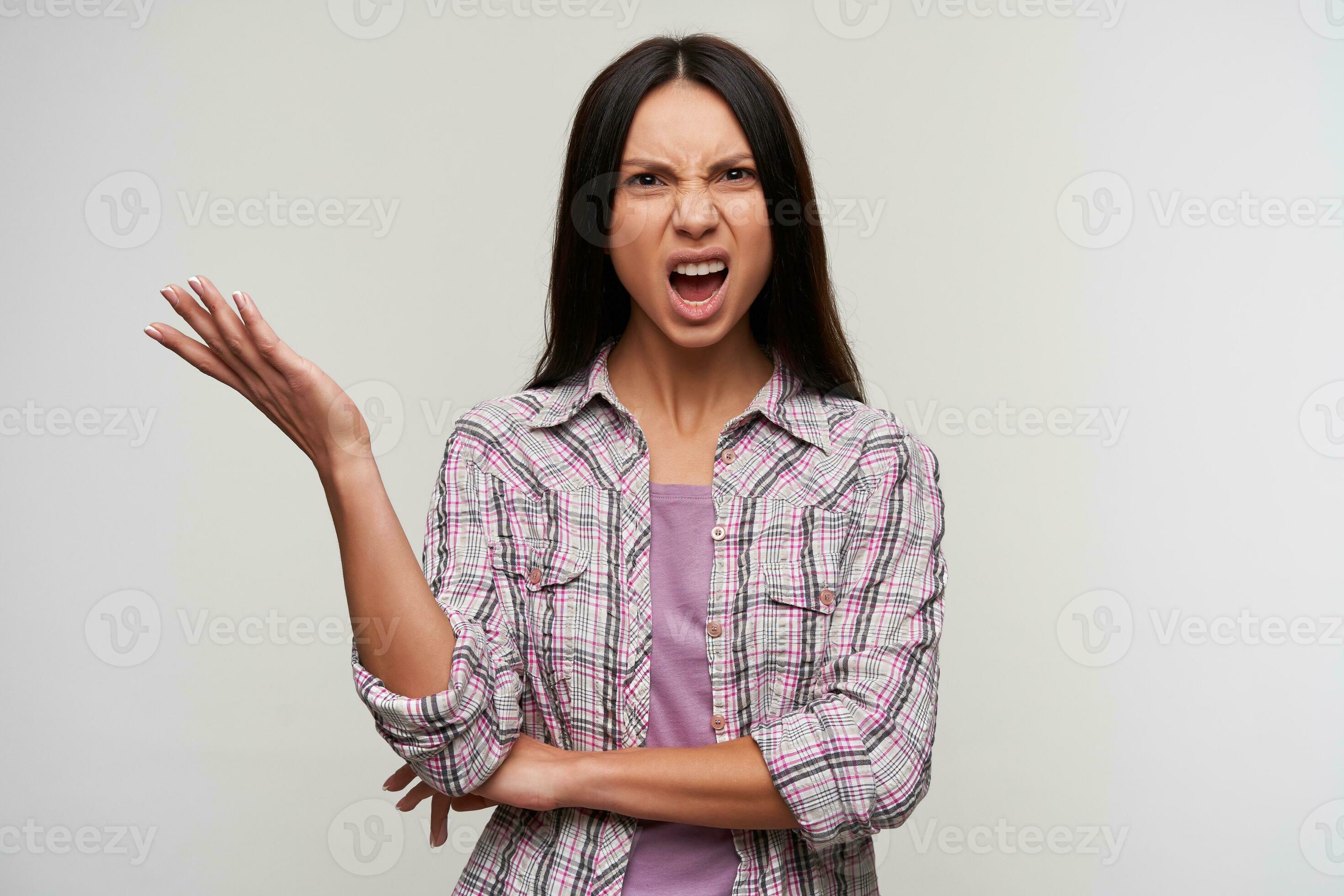 Indignant young dark haired lady with natural makeup raising palm