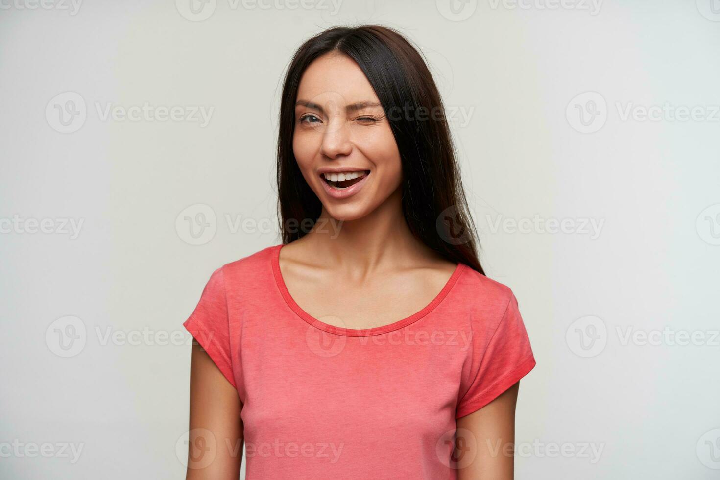 retrato de alegre joven atractivo oscuro peludo mujer con casual peinado dando guiño a cámara y sonriente felizmente, en pie en contra blanco antecedentes foto