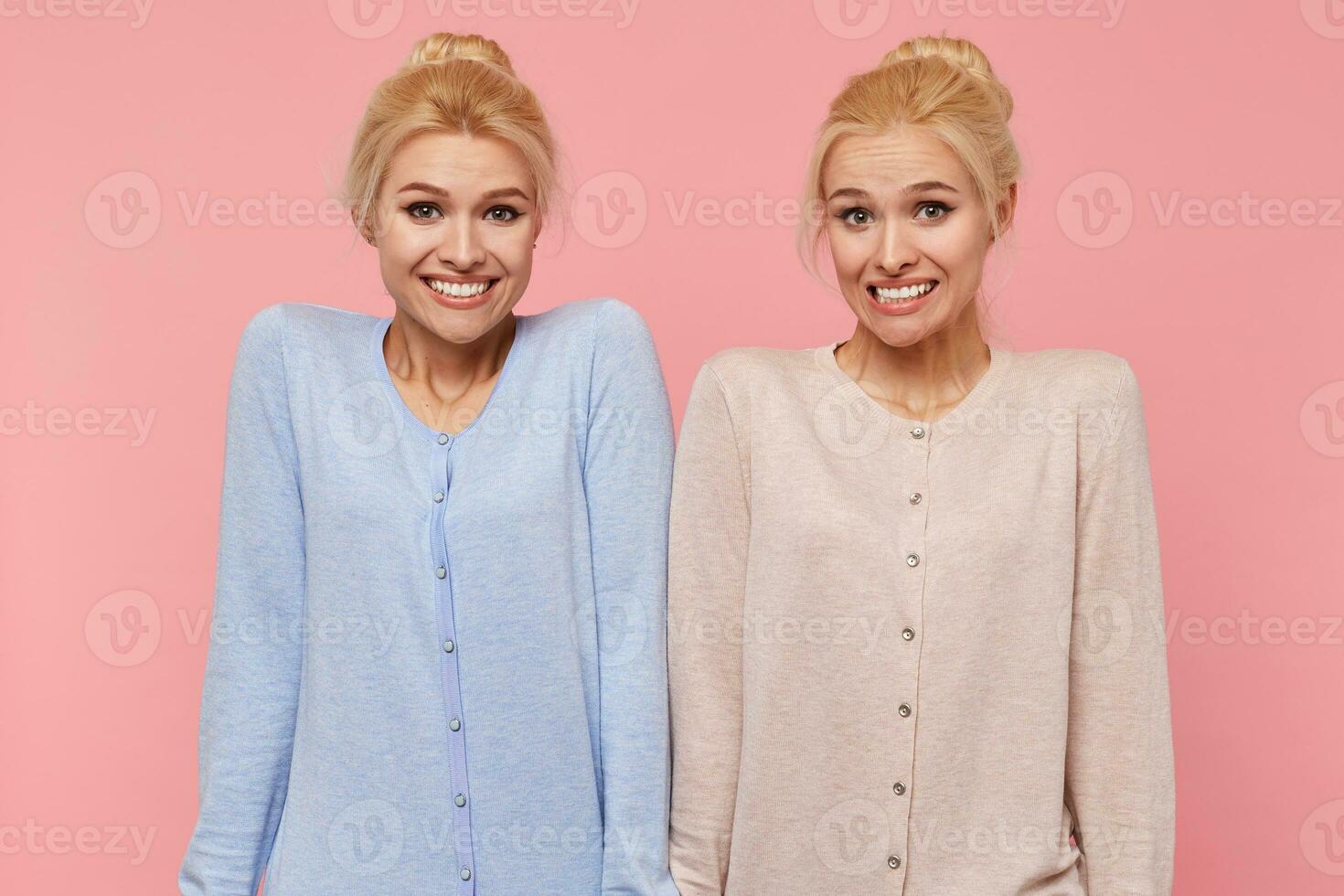 Beautiful young blonde twins confused and unable to explain and understand the current situation, shrug and smile isolated over pink background. photo