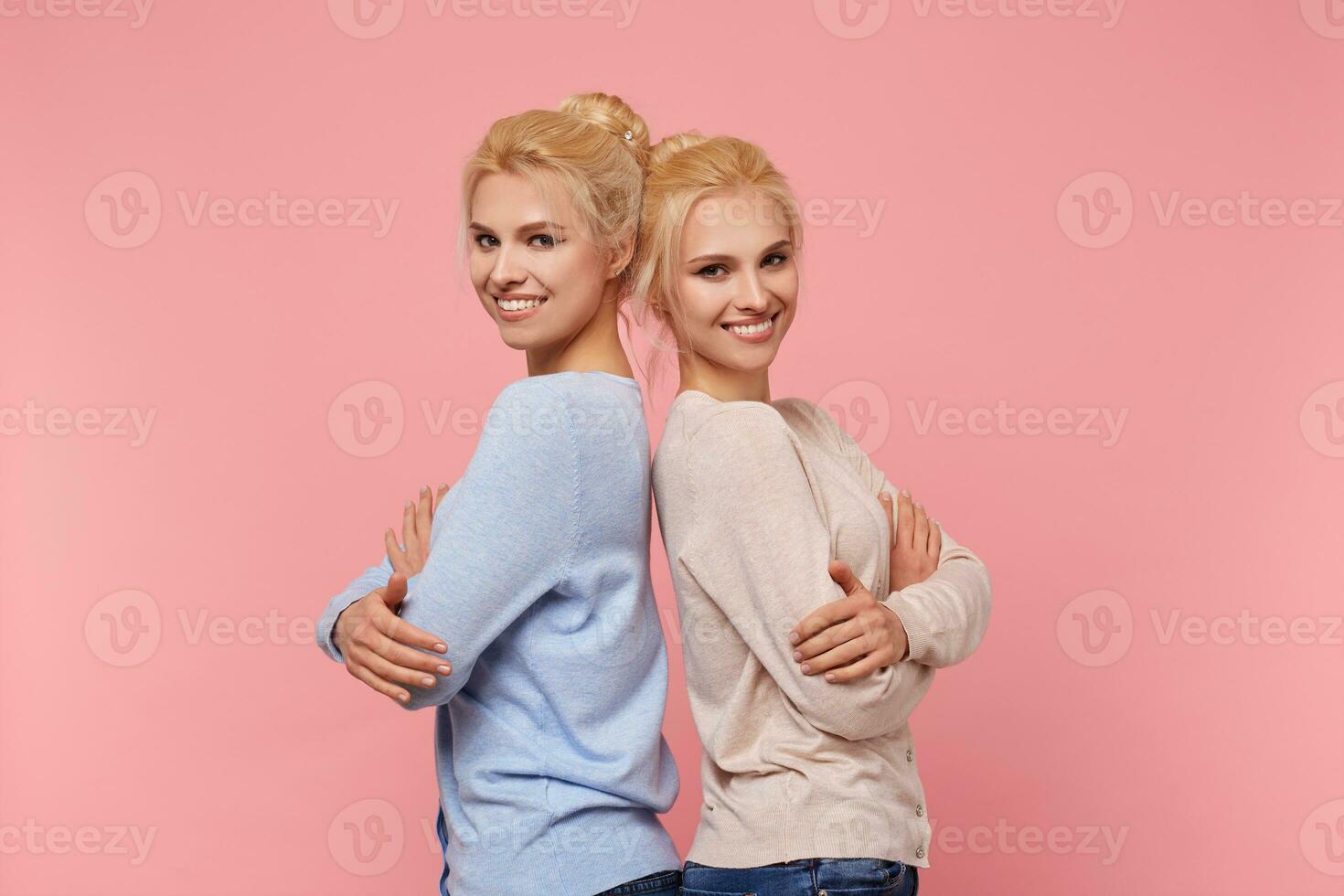 Photos of two twins, sisters - a great team, they will always support each other and help out, they are never bored together Stands over pink background.
