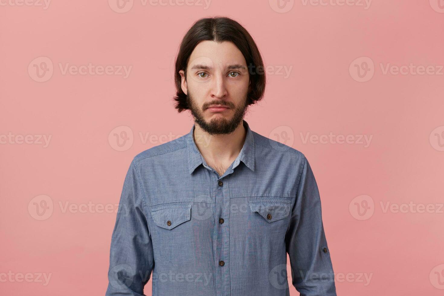 Portrait of young bearded brunet man offended upset depressed, pouted his lips, in bad mood dressed in casual shirt, going to cry, isolated over pink background. photo