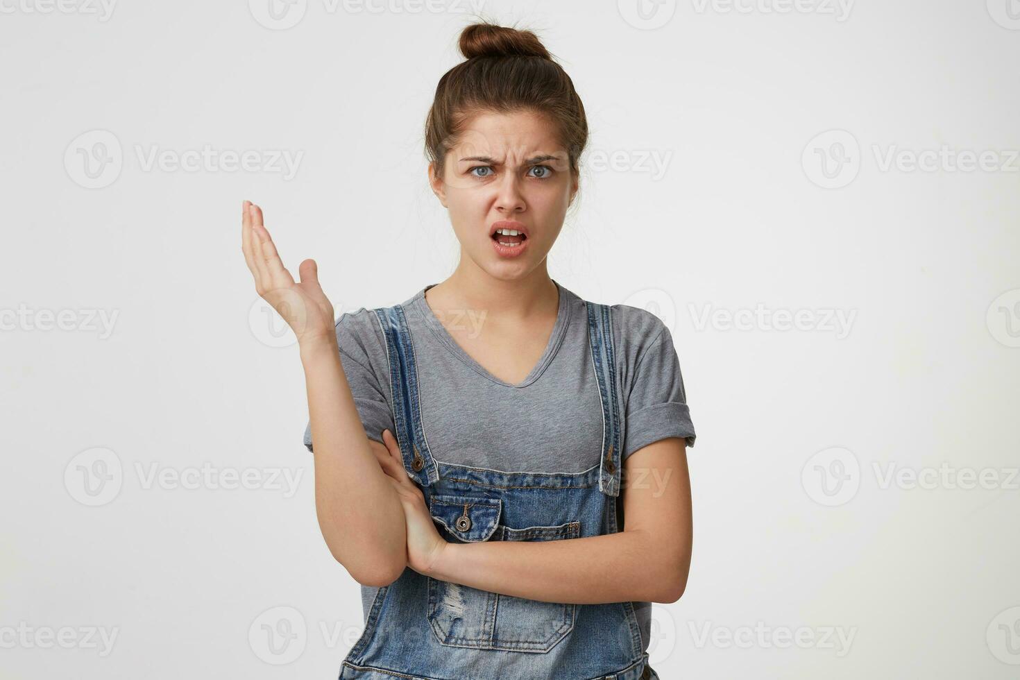 Beautiful girl portrays indignation, discontent, indignation one arm raised,one crossed isolated on white background.Someone said a terrible nonsense. photo