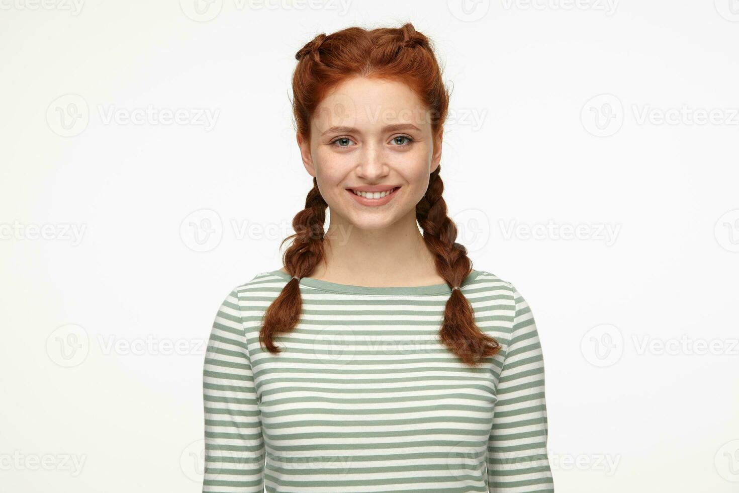 portrait of young ginger female standing over white studio background looking directly into camera with broad smile photo