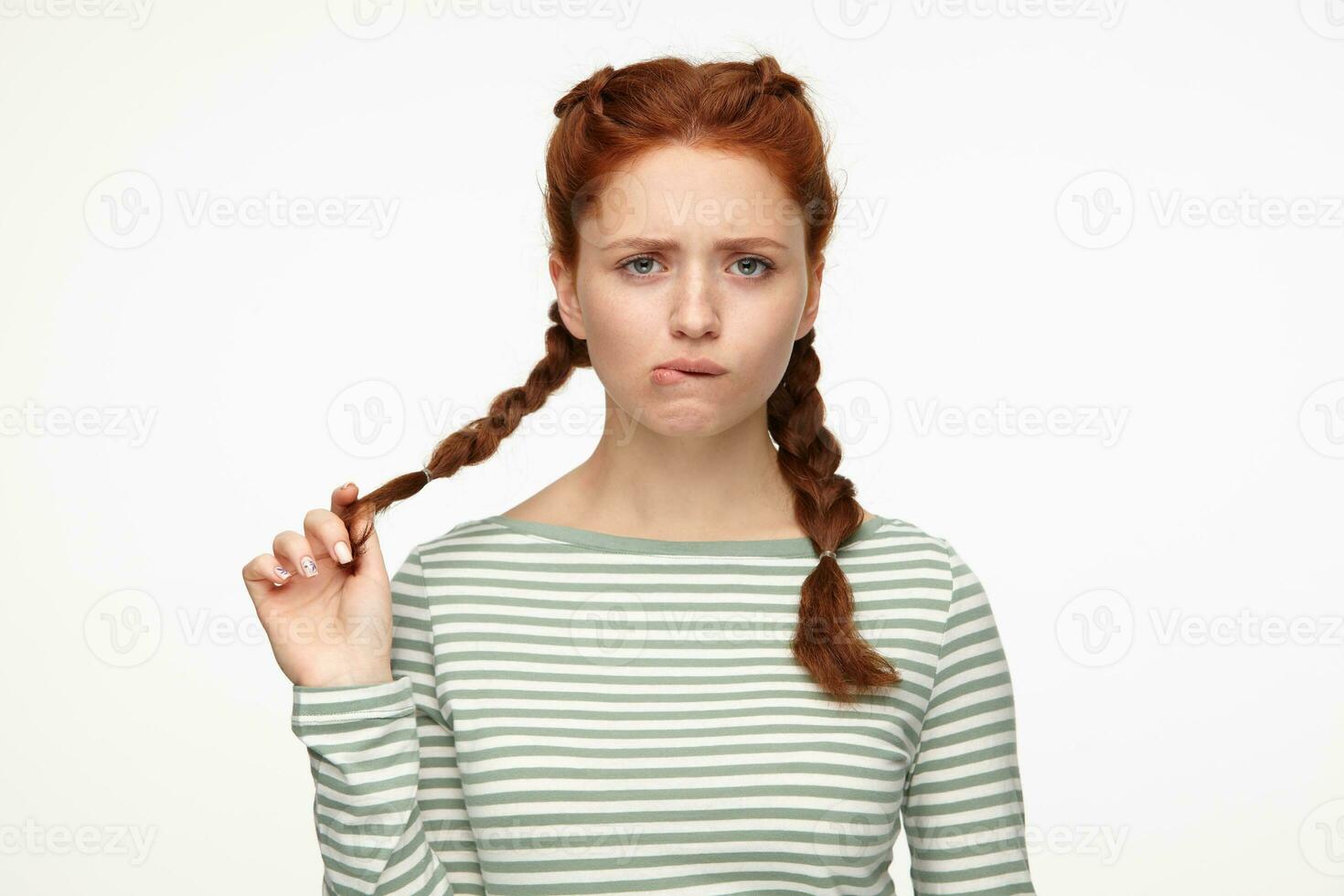 portrait of young ginger female standing over white studio background biting her lip photo