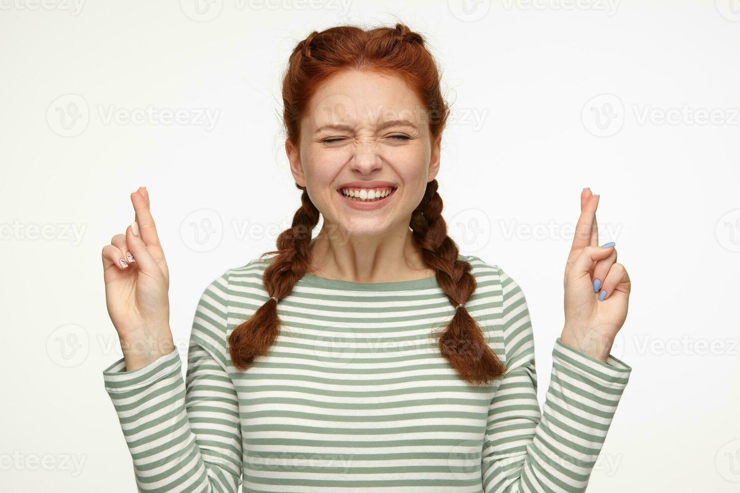 ginger young female keeps her fingers crossed while praying photo