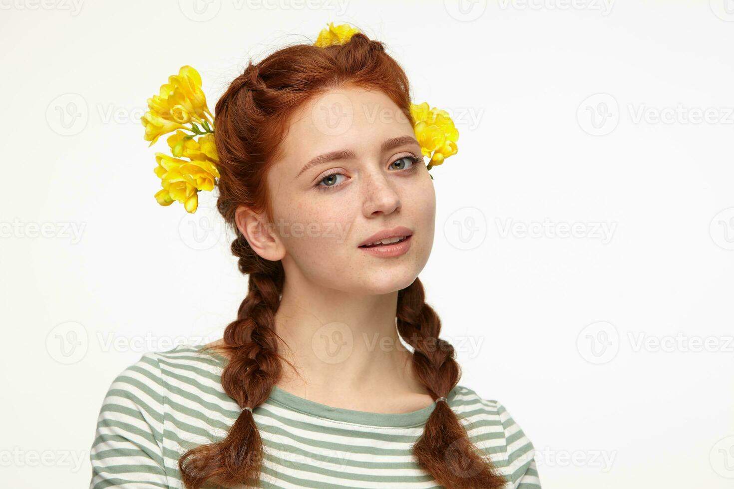 Indoor portrait of young ginger female posing over white background looking into camera with calm facial expression photo