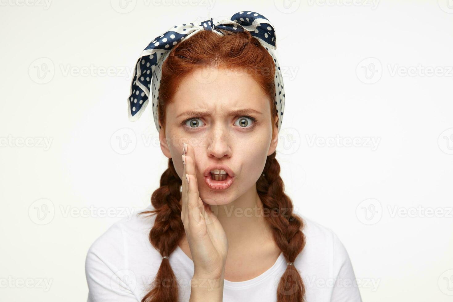portrait of young ginger female standing over white studio background whisper some bad news with angry facial expression photo